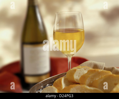 Glas Weißwein auf einem Tisch mit einer Flasche Wein Stockfoto