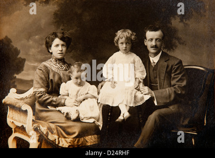 Familiengeschichte, Edwardian Studioportrait von Eltern und zwei kleinen Kindern in Kleider Stockfoto