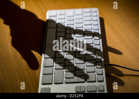 Schatten einer Hand über eine Computer-Tastatur. Stockfoto