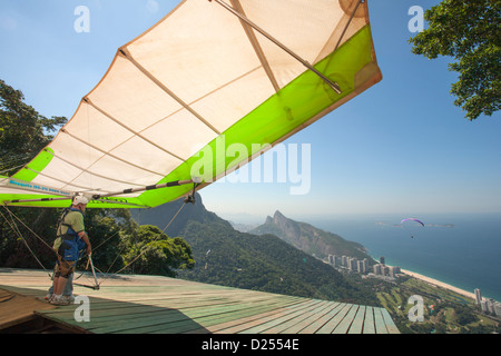 Brasilien, Rio, Tijuca-Wald, Drachenflieger, der sich auf den Start am Pedra Bonita-Felsen oberhalb des Strandes von Sao Conrado vorbereitet. Blick auf den Strand und den Atlantischen Ozean Stockfoto
