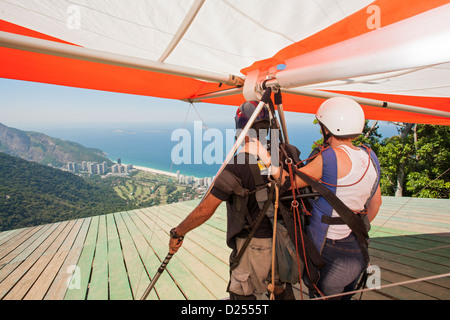 Brasilien, Rio, Tijuca-Wald, Tandem-Drachenflieger, die sich auf den Start am Pedra Bonita-Felsen über dem Strand von Sao Conrado vorbereiten. Blick auf den Strand und den Atlantischen Ozean Stockfoto