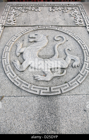 Es ist ein Foto von einem Basrelief oder Flachrelief eines chinesischen Drachen in einen Kreis auf einem flachen Stein. Es ist ein Symbol. Stockfoto