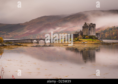 Eilean Donan Castle, Dornie, Schottland, im Winter mit Nebel hinter und ein Loch im Vordergrund Stockfoto