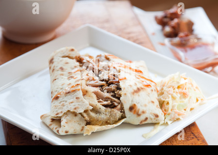 Karibischen Stil Ruckhuhn in traditionellen Roti serviert und beträufelt mit süß scharfer Sauce. Serviert mit einer Seitenlänge von Krautsalat. Stockfoto