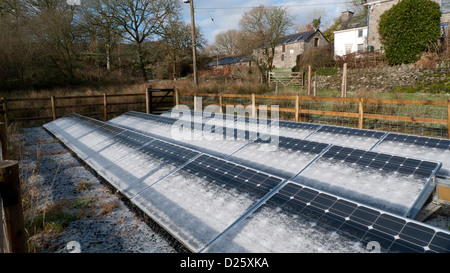 Schneerauf auf bodenmontierten Solarpaneelen und Steinhütten-Scheunen im Winter auf einem Kleinbetrieb in West Wales, Großbritannien KATHY DEWITT Stockfoto