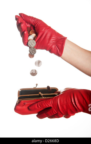 Geld in eine rote Handtasche aus einer roten behandschuhten Hand gießen Stockfoto