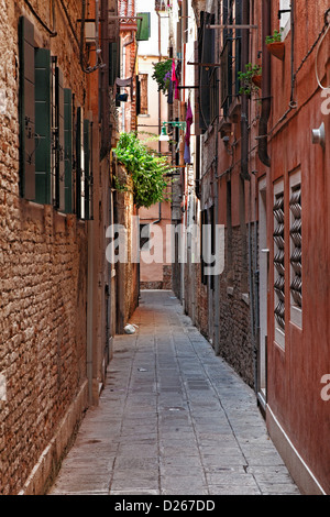 Bild einer typischen schmalen Straße zwischen den Wänden der Häuser in Venedig. Stockfoto