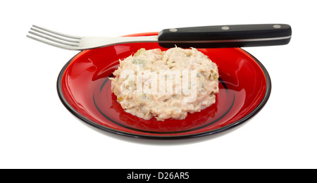 Eine kleine rote Platte mit einer kleinen Portion Thunfisch-Salat mit Gabel auf weißem Hintergrund. Stockfoto