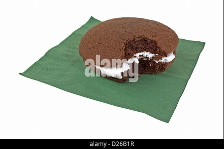 Ein Schokoladen-Whoopie Pie mit Zuckerguss, die auf einem weißen Hintergrund gebissen worden ist. Stockfoto