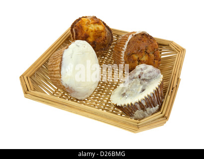 Vier frische Muffins in einem Weidenkorb auf weißem Hintergrund. Stockfoto
