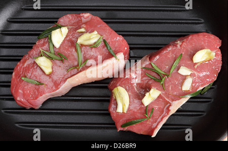 Stücke von Striploin Steak, das mit mariniert wurde Knoblauch, Rosmarin und Olivenöl in einer Grillpfanne bereit, Kochen Stockfoto