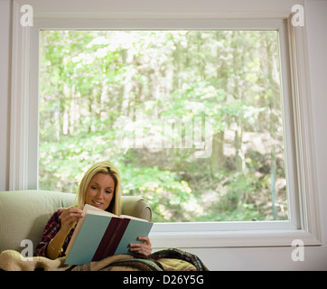 USA, Connecticut, Newtown, Frau auf dem Sofa sitzen und Buch Stockfoto