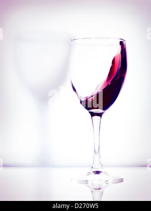 Rotwein in einem Glas künstlerische Foto auf hellen rosa Hintergrund isoliert Stockfoto