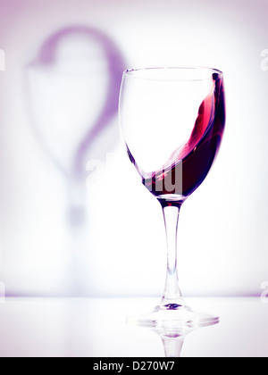 Rotwein in ein Glas und Schatten ein Fragezeichen künstlerische konzeptionelle Foto isoliert auf weißem Hintergrund Lila Stockfoto