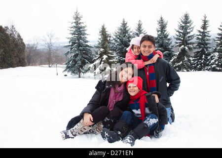 Eine schöne Ost-indischen Eltern spielen mit ihren Kindern im Schnee. Stockfoto