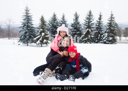 Eine schöne ostindischen Mutter spielt mit ihren Kindern im Schnee. Stockfoto