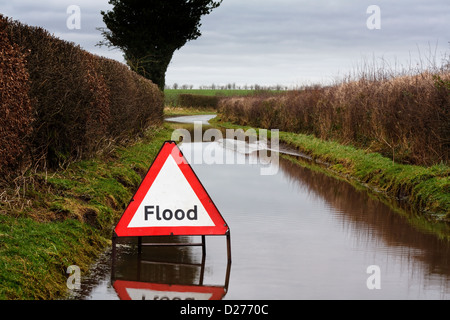 Flut-Warnschild auf einer überfluteten Landstraße mit ungünstigen Fahrbedingungen Stockfoto