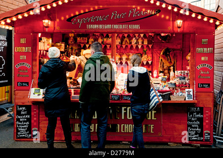 Leute Touristen Besucher am Weihnachtsmarkt Stand, der Schokolade verkauft Winter York North Yorkshire England Großbritannien GB Groß Großbritannien Stockfoto
