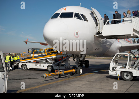 Gepäcktaschen der Verladung in ein Flugzeug und Passagiere Stockfoto