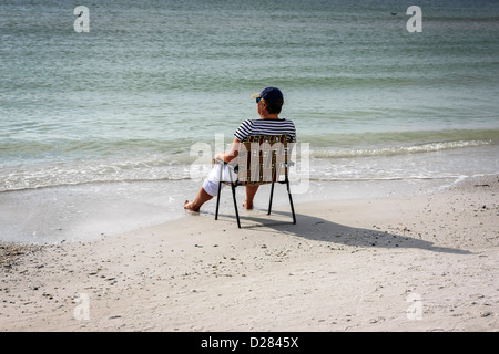 Eine Frau sitzt am Rand Wassers auf Siesta Key Beach im sonnigen Florida Stockfoto