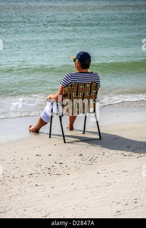 Eine Frau sitzt am Rand Wassers auf Siesta Key Beach im sonnigen Florida Stockfoto