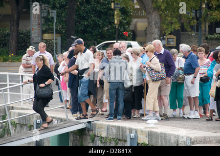 Eine Gruppe von Touristen, die in Sirmione an der Südspitze des Gardasees in der Provinz Brescia in Norditalien an Bord eines der Ausflugsboote gehen. Stockfoto