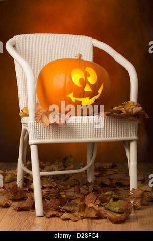 Kürbis auf weißen Stuhl mit Herbst Blätter Stockfoto