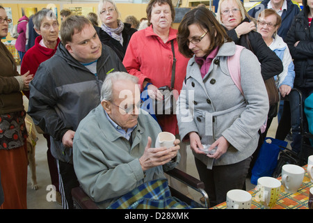 Blinde und sehbehinderte Menschen mit Betreuern auf Ausflug nach Denby Pottery. Krug zu berühren. Stockfoto