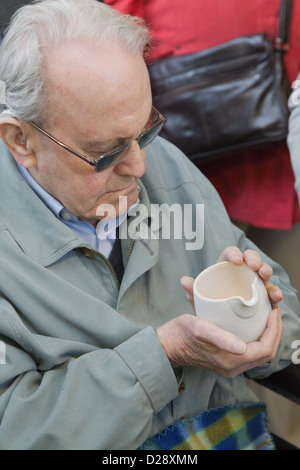 Blinde und sehbehinderte Menschen mit Betreuern auf Ausflug nach Denby Pottery. Krug zu berühren. Stockfoto