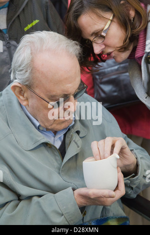 Blinde und sehbehinderte Menschen mit Betreuern auf Ausflug nach Denby Pottery. Krug zu berühren. Stockfoto