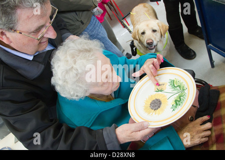 Blinde und sehbehinderte Menschen mit Betreuern auf Ausflug nach Denby Pottery. Berühren die Glasur. Stockfoto