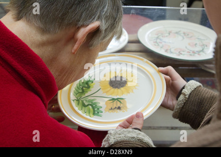 Blinde und sehbehinderte Menschen mit Betreuern auf Ausflug nach Denby Pottery. Inspektion der Glasur. Stockfoto