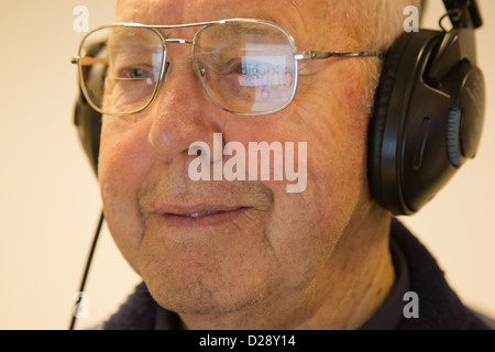 Computer-Klasse für Menschen mit Sehbehinderungen - Mann mit Kopfhörern für Audio, reflektiert Google in seiner Brille. Stockfoto