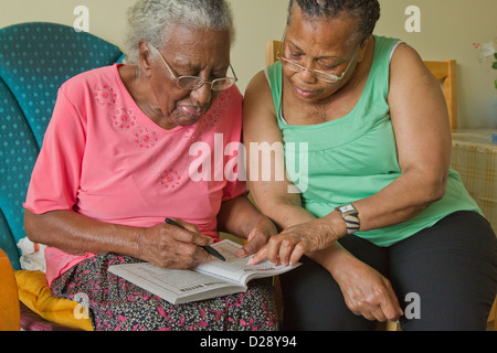 Betreuer und älteren Menschen beeinträchtigt visuell Frau Kreuzworträtsel zu lösen. Stockfoto