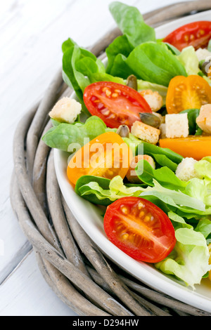 Salat mit Tomaten und Croutons auf einem Teller - frisches und gesundes Mittagessen auf einem rustikalen Holztisch Stockfoto