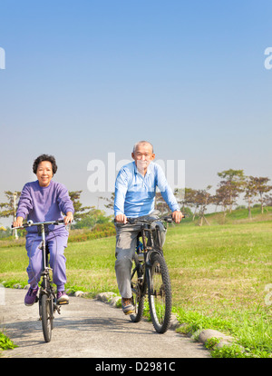 Glücklich asiatischen Senioren paar Radfahren im park