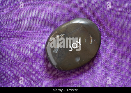 Fair-Trade-Stimmung-Kiesel - Joy pebble isoliert auf lila Hintergrund Stockfoto