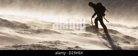 Mountain Rescue Mitglied geht über Hügel während der harten winterlichen Bedingungen in den schottischen Highlands in der Nähe von Nevis range Stockfoto