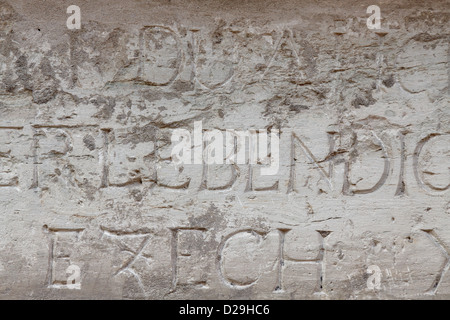 Fragment der Innenwand der alten katholischen Kathedrale. Es gibt Wörter und Buchstaben an der Wand in lateinischer Sprache geschnitzt. Stockfoto