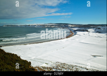 WINTER SCHNEE LIEGT AUF DEN STRAND UND GOLFPLATZ IN CULLEN BAY MIT DER STADT CULLEN IN DER FERNE Stockfoto