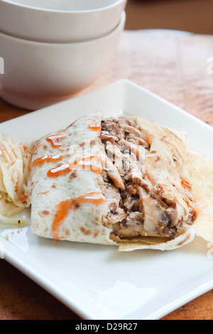 Karibischen Stil Ruckhuhn in traditionellen Roti serviert und beträufelt mit süß scharfer Sauce. Serviert mit einer Seitenlänge von Krautsalat. Stockfoto