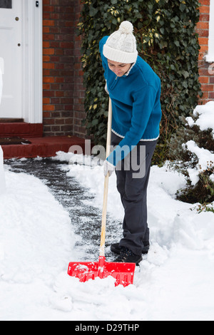 Person Schaufeln Schnee ab Einfahrt vor ihrem Haus Stockfoto