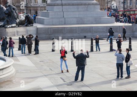 Frau Tourist nutzt ihr Handy, ein Foto von einem Mann am Trafalgar Square in London machen. Stockfoto