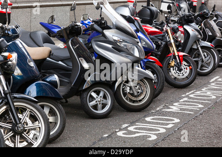 Reihe von geparkten Motorroller und Motorräder in einen dafür vorgesehenen Parkplatz in der City of London. Stockfoto