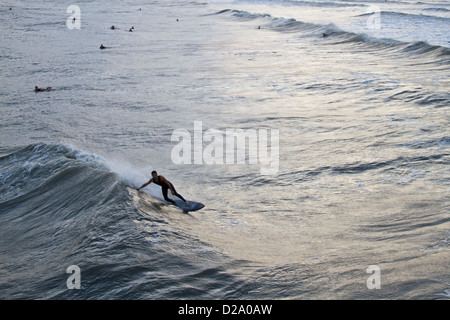 eine Surfer auf einer Welle von Hurrikan Sandy ist in Folly Beach, South Carolina, während andere Surfer schauen auf. Stockfoto