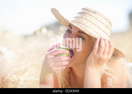 Frau zu essen Apfel in hohe Gräser Stockfoto