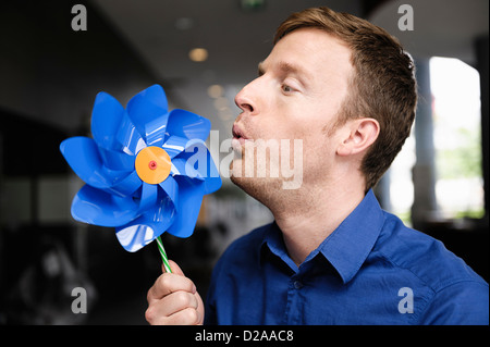 Mann bläst Windrad drinnen Stockfoto