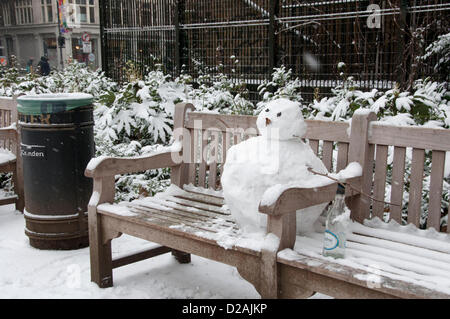 London, UK. 18.01.13. Ein Schneemann mit einer Flasche Wein sitzt auf einer Parkbank in der Nähe von Tottenham Court Road, als Schnee im Zentrum von London fällt. Stockfoto