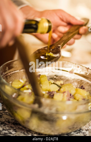 Man gießt Olivenöl in Salat Stockfoto