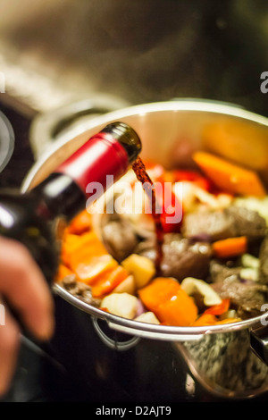 Man gießt Wein in Gemüse Stockfoto